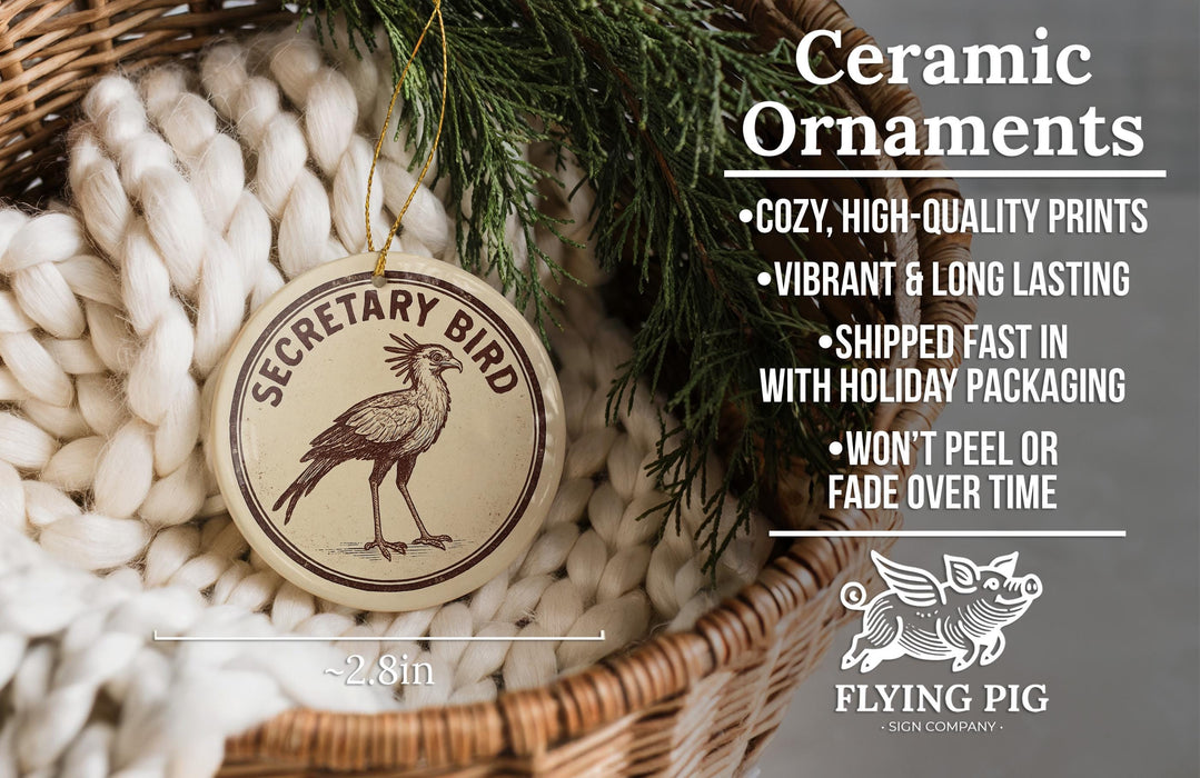 Ceramic ornaments, featuring a Secretary Bird ornament, are displayed in a basket with a pine branch.