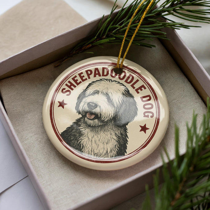 A circular ornament featuring a dog's face, with the text "SHEPADOOD" and "DOG" printed on it, is displayed in a box surrounded by pine branches.