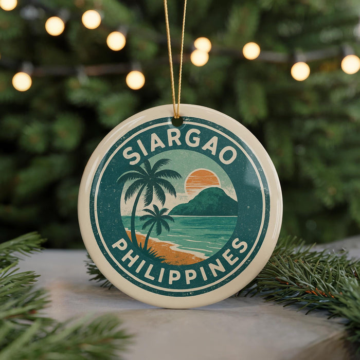 A circular ornament with the text "SIARGAO PHILIPPINES" and a tropical beach scene, featuring palm trees and a sunset, is displayed in front of a Christmas tree with lights.