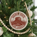 A Christmas tree decorated with ornaments, including a circular ornament with the text "SIGIRIYA ROCK" and "SRI LANKA" printed on it.