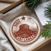 A circular ornament with the text "SIGIRIYA ROCK" and "SRI LANKA" printed on it, hanging from a string.