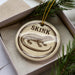 A ceramic ornament in a box, featuring a detailed illustration of a lizard or salamander.