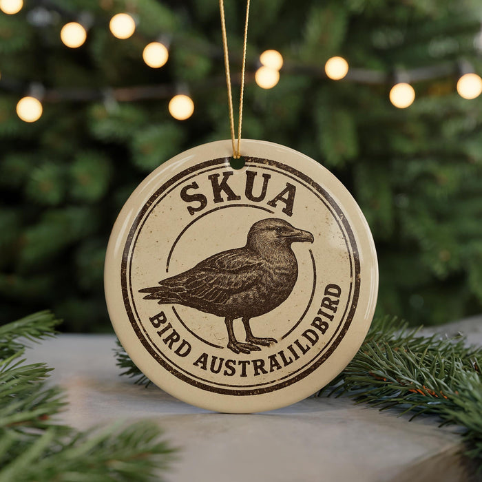 A circular ornament with the text "SKUA BIRD AUSTRALIALDBIRD" and an illustration of a bird, placed on a surface with pine branches in the background.
