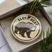 A circular ornament with the text "SLOT. BEAR" printed on it, featuring a black and white illustration of a sloth bear.