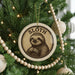 A Christmas tree decorated with ornaments, including a circular ornament featuring a sloth.