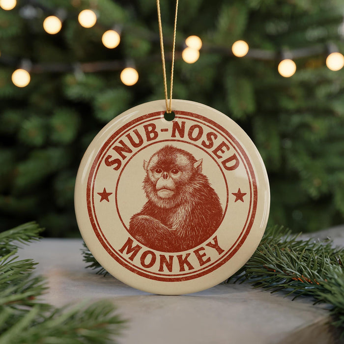 A round ornament with a monkey image and the text "SNUB-NOSED MONKEY" printed on it, hanging from a string.