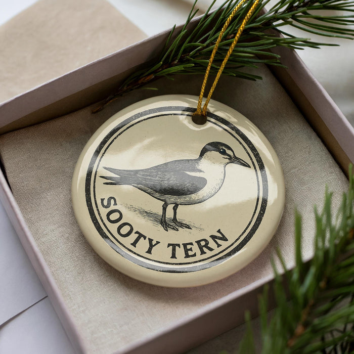 A ceramic ornament in a box, featuring a black and white illustration of a bird and the text "Sooty Tern" on it.