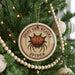 A Christmas tree decorated with ornaments, including a round ornament with a spider image and the text "SPINNY ORB-WEAVER SPIDER".