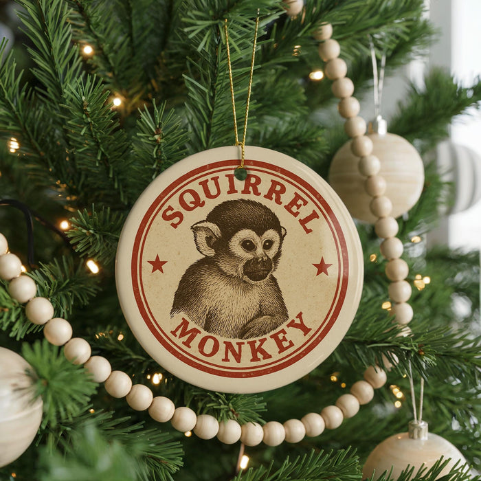 A round ornament with a monkey image is hanging on a Christmas tree, surrounded by other ornaments and lights.