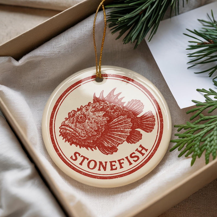 A round ornament with a red and white design featuring a fish, hanging from a string.