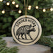 A round ornament featuring a striped hyena, with the text "STRIPED HYENA" printed on it.