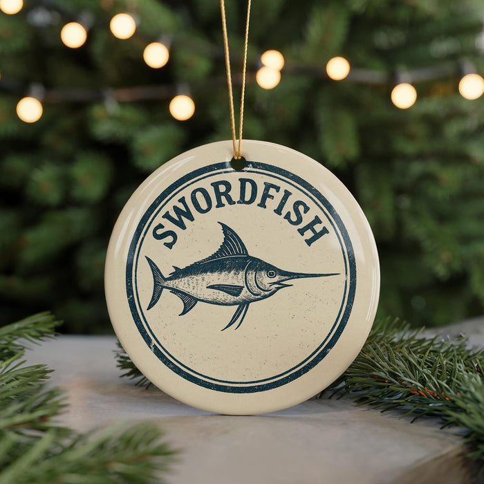 A round ornament with the word "SWORDFISH" and a graphic of a swordfish is displayed against a blurred background of a Christmas tree with lights.