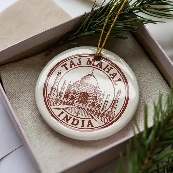 A decorative ornament featuring the Taj Mahal, a famous mausoleum in India, is displayed in a box with pine branches.