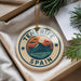 A decorative ornament with the text "Tenerife Spain" and a graphic of a mountain landscape with palm trees, hanging from a string.