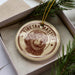 A Tibetan Mastiff ornament is displayed in a box, surrounded by pine branches.