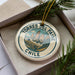 A decorative ornament in a box, featuring a mountain landscape with the text "TORRES DEL PAINE CHILE" around the edge.