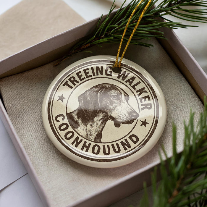 A circular ornament with a dog image and the text "TREEING WALKER COONHOUSE" printed on it, placed inside a box with pine branches.