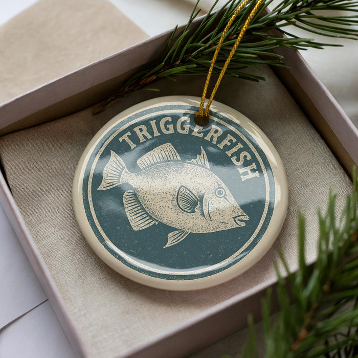 A circular ornament with the word "TRIGGERFISH" printed on it, surrounded by pine branches.