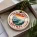 A circular ornament with the text "TROLLUNGA NORWAY" printed on it, surrounded by pine branches.