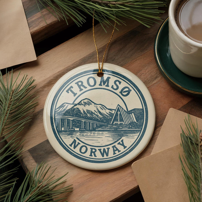 A circular ornament with the text "TROMSO NORWAY" and an illustration of a bridge and mountains, hanging on a wooden surface.