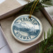 A circular ornament with the text "TROMSO NORWAY" printed on it, surrounded by pine branches.