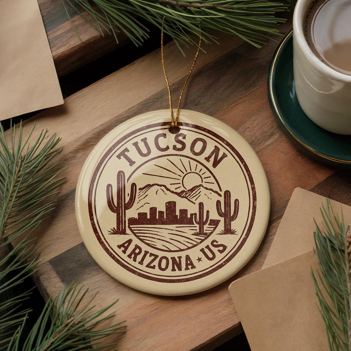 A circular ornament with the text "TUCSON ARIZONA US" printed on it, surrounded by pine branches and a cup of coffee on a wooden surface.