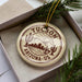 A circular ornament with the text "TUCSON ARIZONA US" printed on it, surrounded by pine branches.