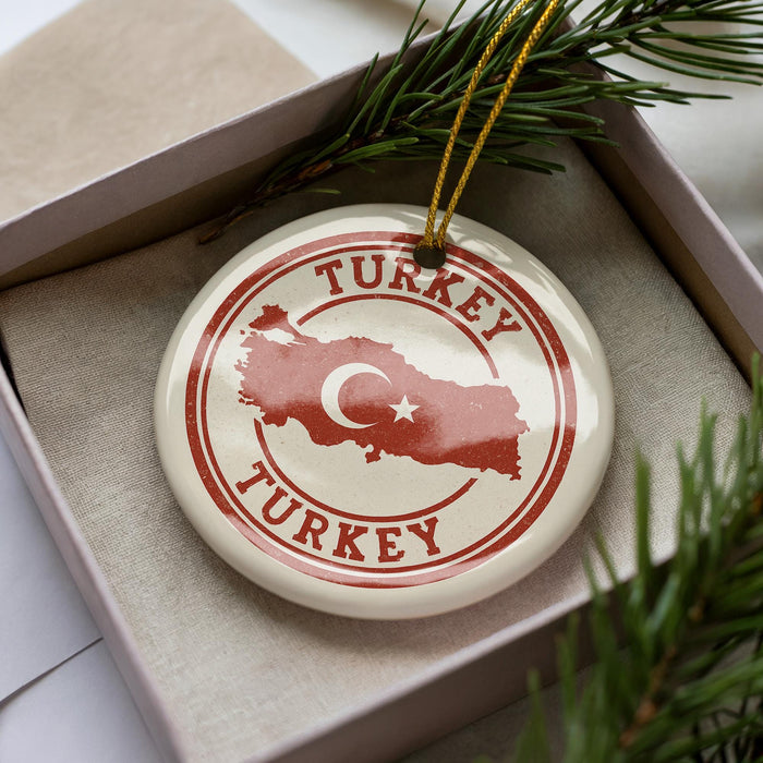 A circular ornament with the word "TURKEY" and a map of Turkey, placed inside a box with pine branches.