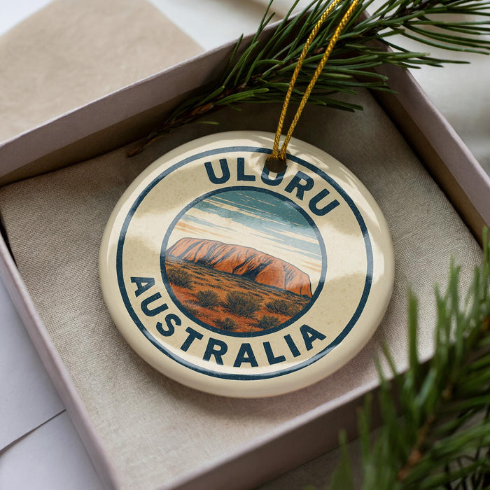 A circular ornament with the text "ULORU AUSTRALIA" printed on it, surrounded by a border and a graphic of Uluru, a famous rock formation in Australia.