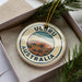 A circular ornament with the text "ULORU AUSTRALIA" printed on it, surrounded by a border and a graphic of Uluru, a famous rock formation in Australia.