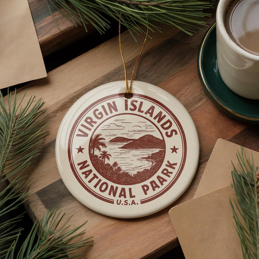 A round ornament with the text "VIRGIN ISLANDS NATIONAL PARK U.S.A." printed on it, surrounded by pine branches and a cup of coffee on a wooden surface.