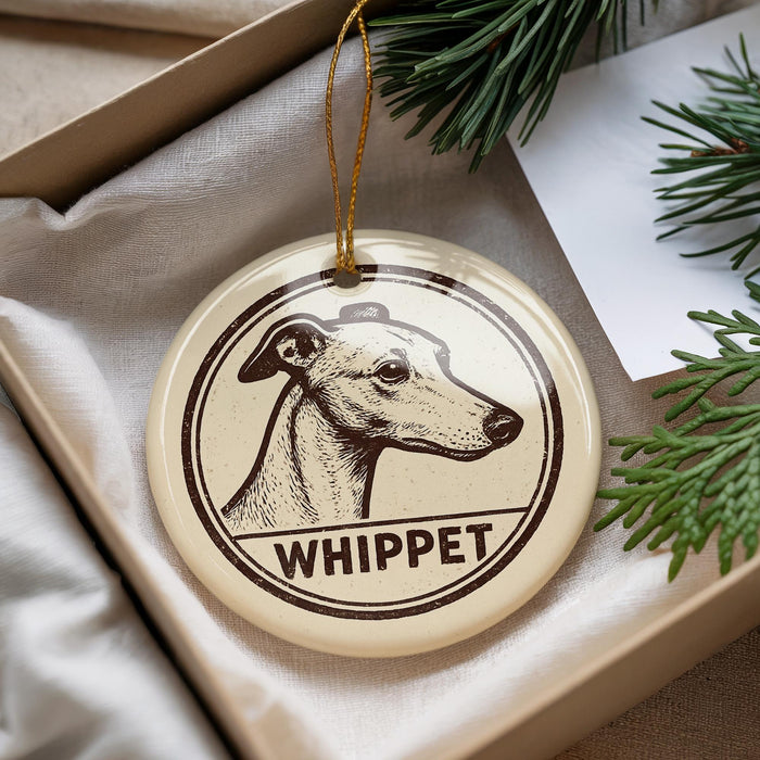 A round ornament with a dog's head and the word "WHIPPET" printed on it, hanging from a string.