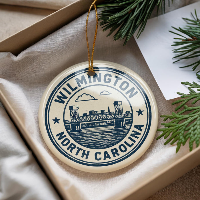 A round ornament with a blue and white design, featuring a bridge and the text "WILMINGTON NORTH CAROLINA".