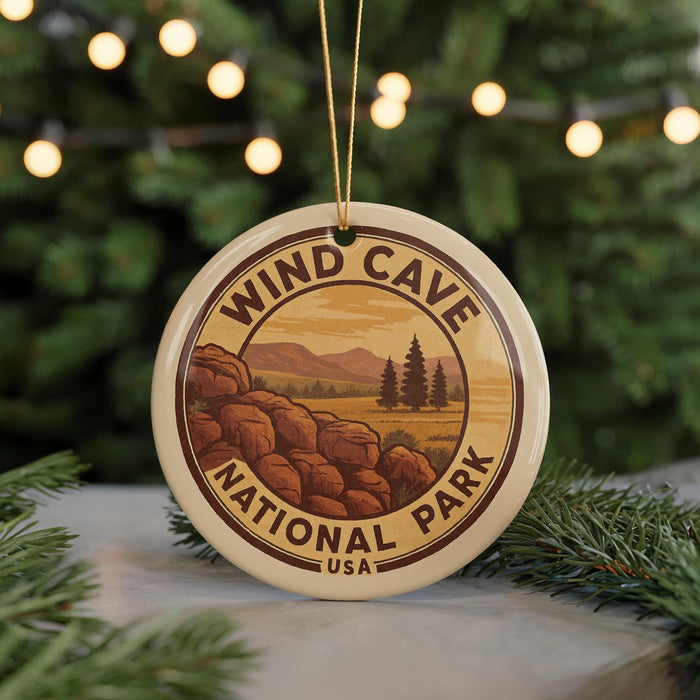 A circular ornament with the text "WIND CAVE NATIONAL PARK USA" and an illustration of a scenic landscape with mountains, pine trees, and rocky formations.