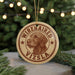 A circular ornament featuring a wirehaired vizSLA dog's head, with the text "WIREHAIRED VIZSLA" printed on it. The ornament is hanging from a string, and there are pine branches visible in the background.