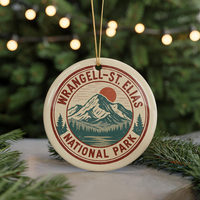 A circular ornament with the text "WRANGEL-ST ELIAS NATIONAL PARK" and a mountain landscape design, hanging from a string.