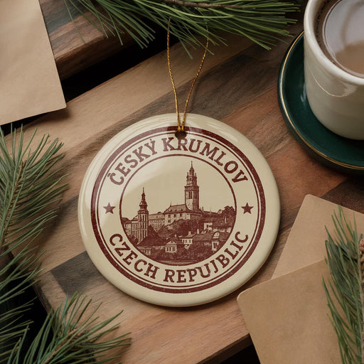 A circular ornament with the text "CESKY KRUMLOV CZECH REPUBLIC" printed on it, surrounded by pine branches and a cup of coffee on a wooden surface.