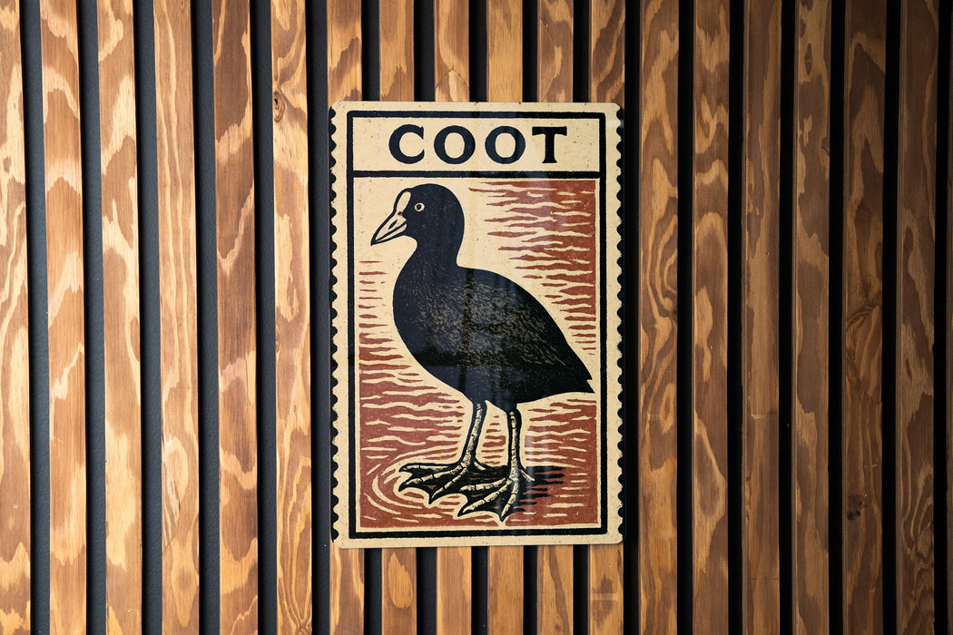 a wooden wall with a framed illustration of a black bird, which appears to be a type of waterfowl.