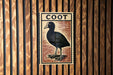 a wooden wall with a framed illustration of a black bird, which appears to be a type of waterfowl.