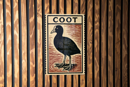 a wooden wall with a framed illustration of a black bird, which appears to be a type of waterfowl.