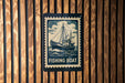 A sign with a fishing boat illustration is mounted on a wooden wall.