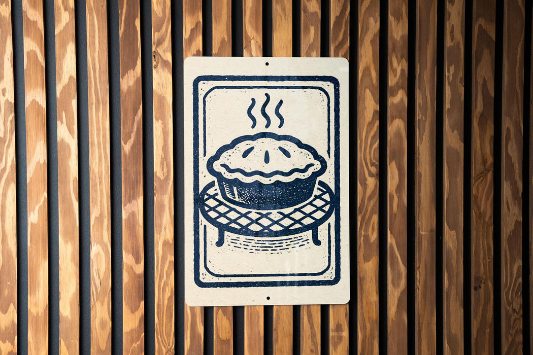 A sign with a pie on it is displayed on a wooden wall.