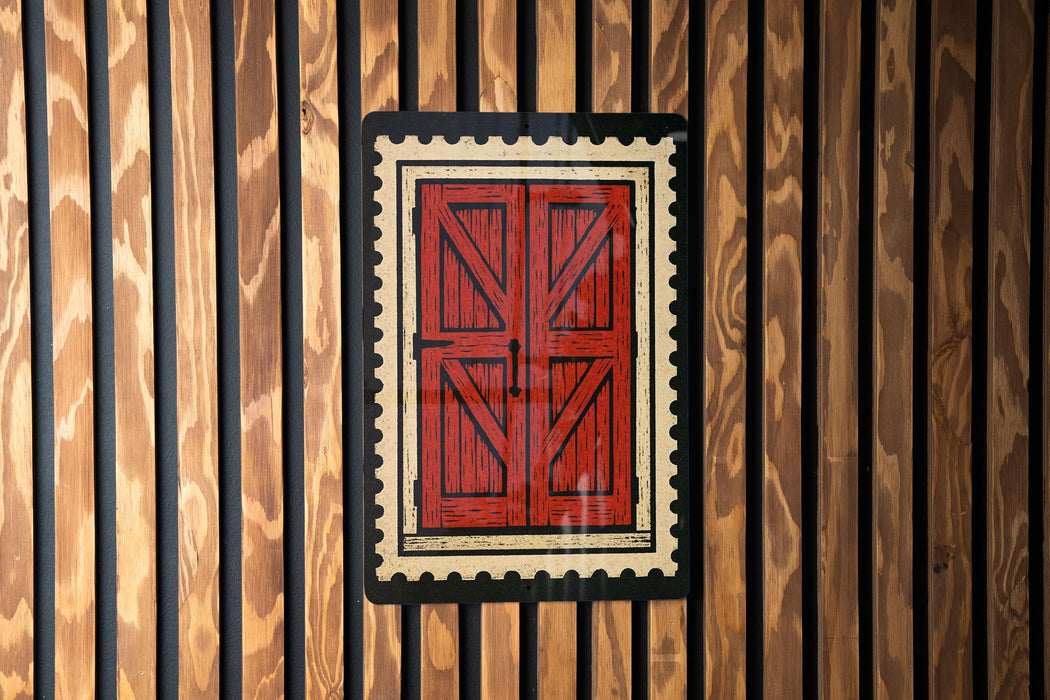 a red wooden door with a black border, set against a wooden wall with vertical slats.