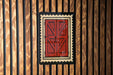a red wooden door with a black border, set against a wooden wall with vertical slats.