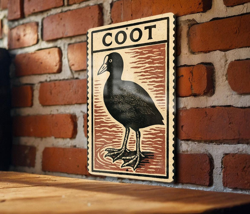 a wooden table with a framed illustration of a black bird, which appears to be a Coot, mounted on a brick wall.