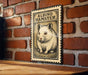A metal sign featuring an illustration of a hamster is mounted on a brick wall.