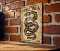 a wooden table with a decorative sign featuring a snake on it, mounted on a brick wall.