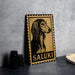 A metal sign with a stylized illustration of a dog's head and the word "Saluki" printed on it, placed on a gray countertop next to some black camera lenses.