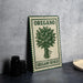 a metal sign with a green border and the word "OREGANO" prominently displayed, along with a depiction of a bunch of oregano leaves.