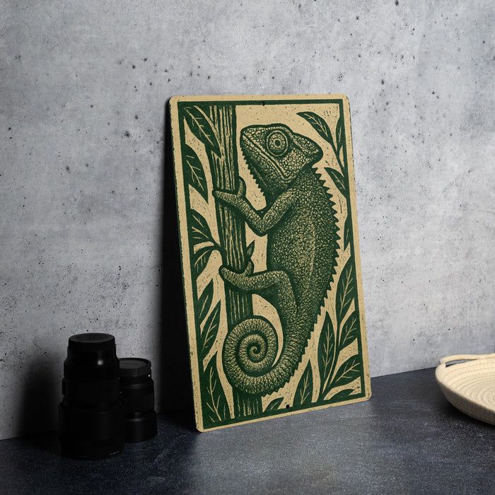 a wooden panel with a detailed illustration of a chameleon on a tree branch, placed on a dark surface next to some black camera lenses.